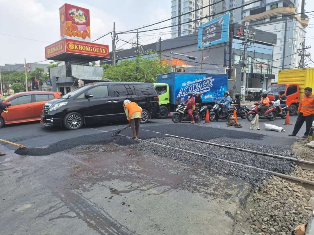 Pengaspalan yang dilakukan di jalan rel JPL 25, Jalan Jenderal Ahmad Yani, Wonokromo, pada Jumat 15 Desember 2023. (Foto: Julianus Palermo/Ngopibareng.id)