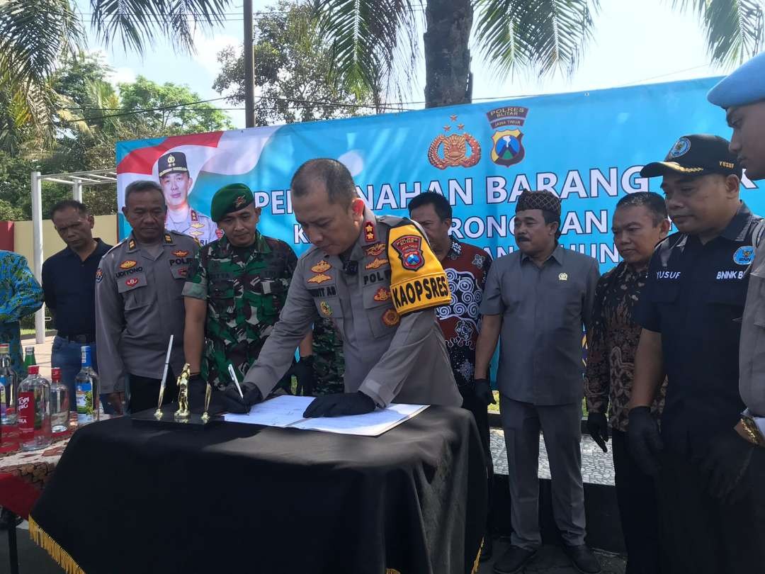 Kapolres Blitar, AKBP Wiwit Adisatria menandatangani berita acara pemusnahan barang bukti miras dan knalpot brong di depan Mapolres Kabupaten Blitar, Jumat 29 Desember 2023. (Foto: Choirul Anam/Ngopibareng.id)