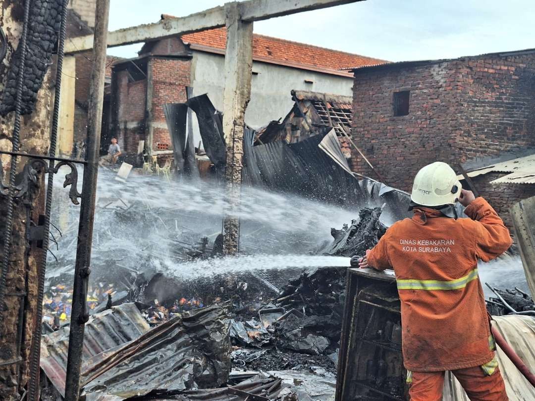 Proses pembasahan oleh tim Dinas Pemadam Kebakaran dan Penyelamatan Surabaya terhadap gudang yang ludes terbakar di Jepara, Surabaya, pada Senin 1 Januari 2024. (Foto: Julianus Palermo/Ngopibareng.id)