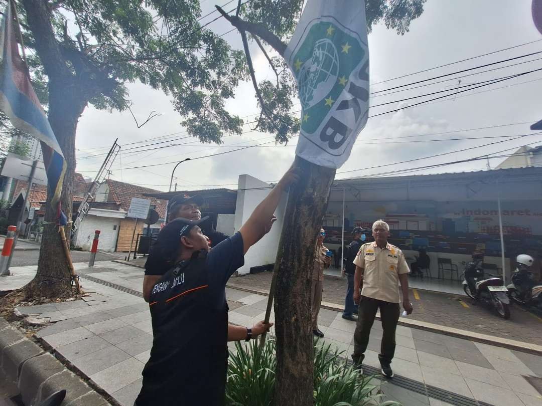 Petugas gabungan Panwascam Gayungan dan Satpol PP Kota Surabaya melakukan pencopotan APK di depan Indomaret Jalan Jenderal Ahmad Yani, Surabaya, Sabtu 6 Januari 2024. (Foto: Julianus Palermo/Ngopibareng.id)