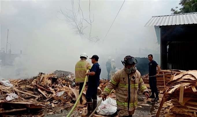 Petugas Damkar Bondowoso memadamkan api membakar limbah pabrik triplek dibantu guyuran hujan, Senin 8 Januari 2024.(Foto: Damkar Satpol PP Bondowoso)