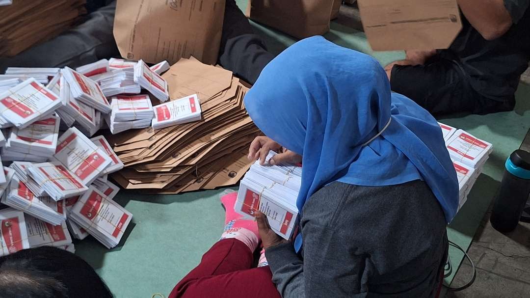 Seorang petugas menghitung jumlah surat suara DPD-RI, sebelum dikemas dan dimasukkan ke kotak suara. (Foto: Julianus Palermo/Ngopibareng.id)