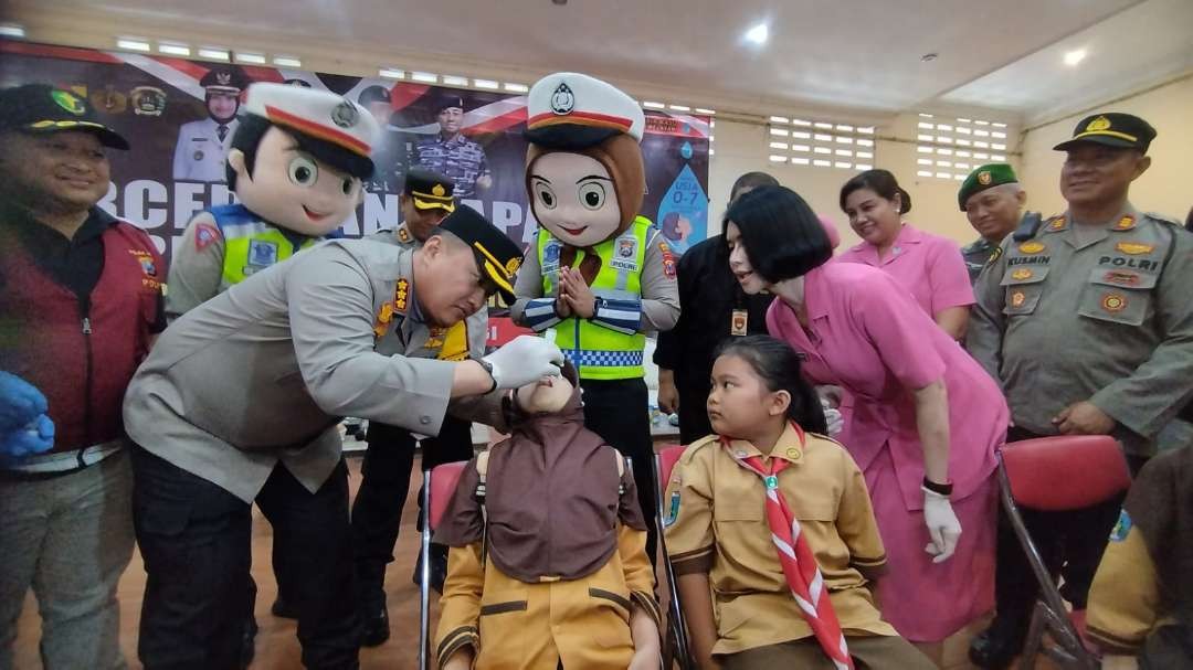 Kapolresta Banyuwangi memberikan imunisasi polio pada seorang siswi SD. (Foto: Muh Hujaini/Ngopibareng.id)