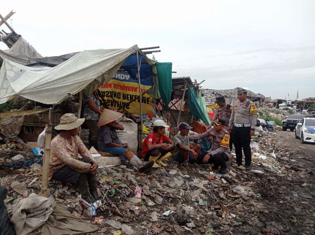 Polisi saat mendengar keluh kesah para pemulung usai berbagi nasi bungkus di TPA Pakusari (Foto: Rusdi/Ngopibareng.id)