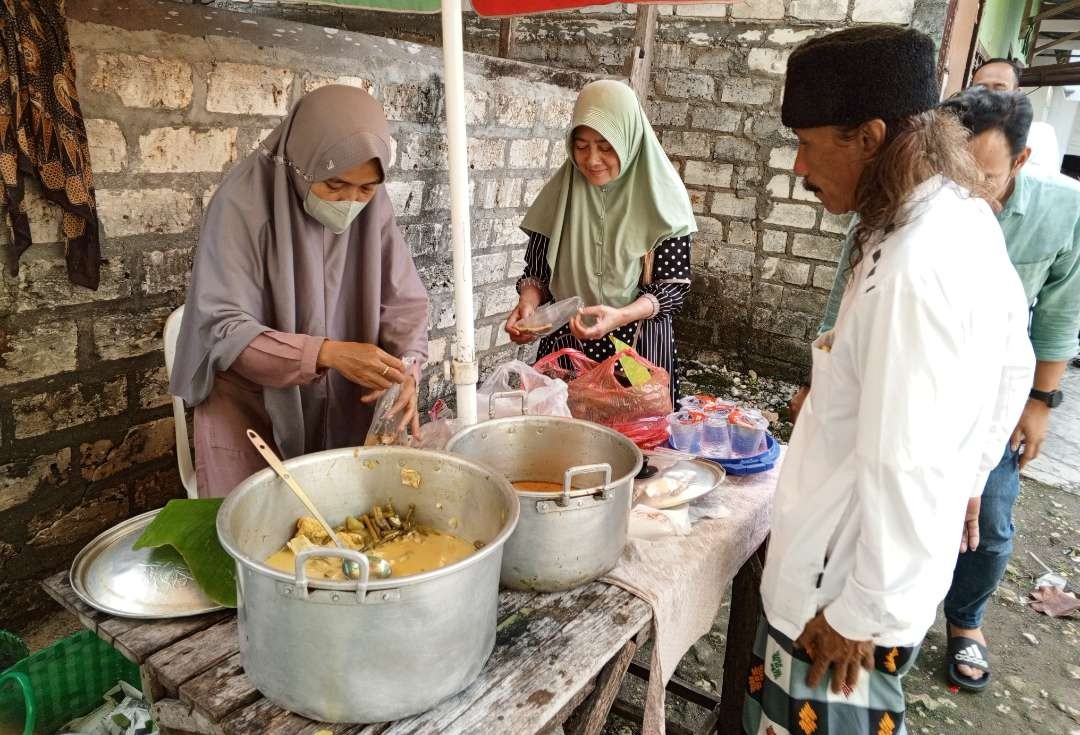 Ibu Nuraini sedang melayani pelanggan sego nggawan yang dijualnya. (Foto: Imron Rosidi/Ngopibareng.id)