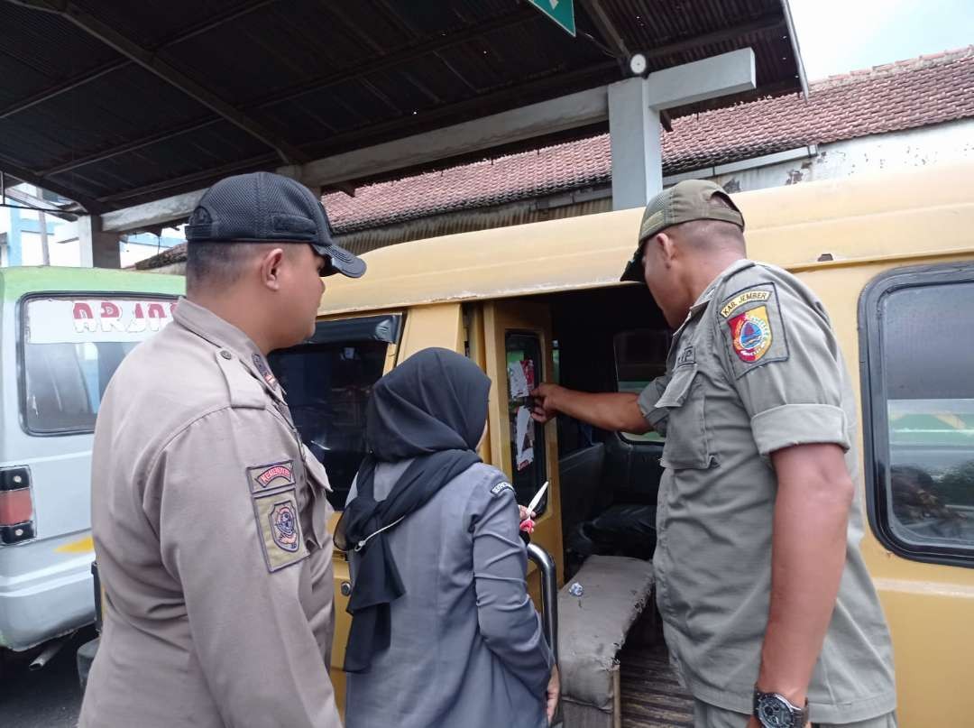 Tim gabungan membersihkan APK berupa stiker tempel di dalam angkot. (Foto: Rusdi/Ngopibareng.id)