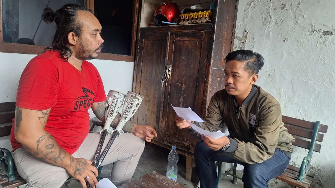 Salah satu petugas KPPS disabilitas Khusnul Yakin, bersama Ketua PPK Wonokromo Divisi Teknis Muhammad Arif Widianto, saat menerangkan formulir C-1 Undangan, Selasa 13 Februari 2024. (Foto: Julianus Palermo/Ngopibareng.id)