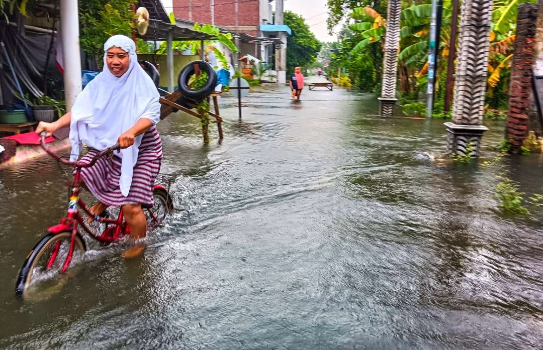 Warga Desa Trosobo beraktivitas di tengah banjir (foto: Aini/Ngopibareng.id)