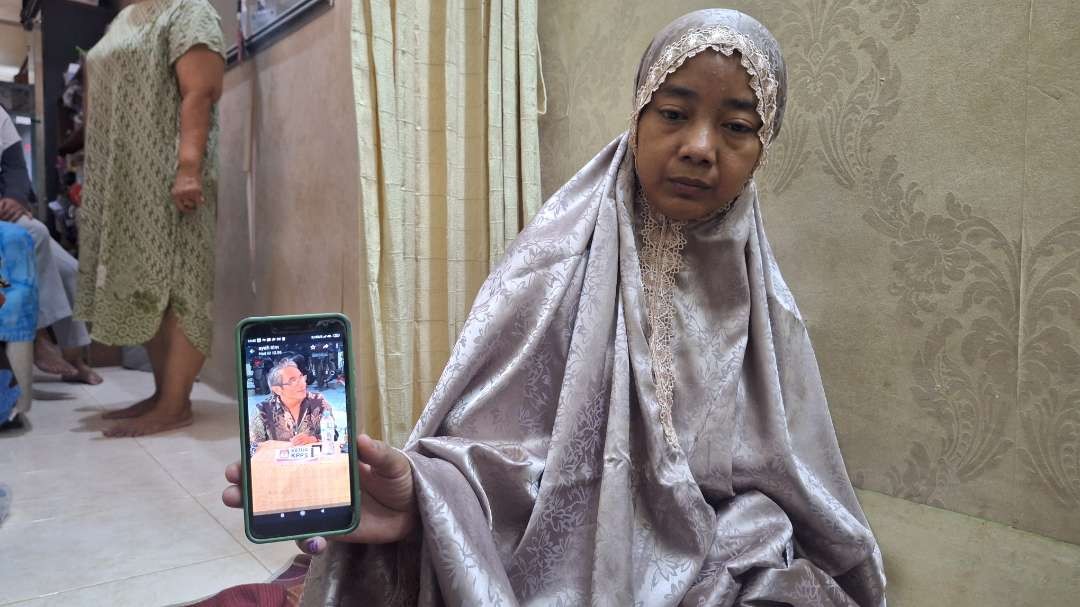 Istri mendiang Ketua KPPS TPS 42 Ngagel Rejo, Wonokromo, Surabaya Joko Budiono, Fauziah Kadir, saat memegang potret sang suami ketika bertugas sebagai Ketua KPPS. (Foto: Julianus Palermo/Ngopibareng.id)