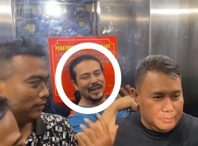 Gathan Saleh (dilingkari) tampak ceria dan santai tangan tak diborgol dalam kawalan polisi. (Foto: Istimewa)