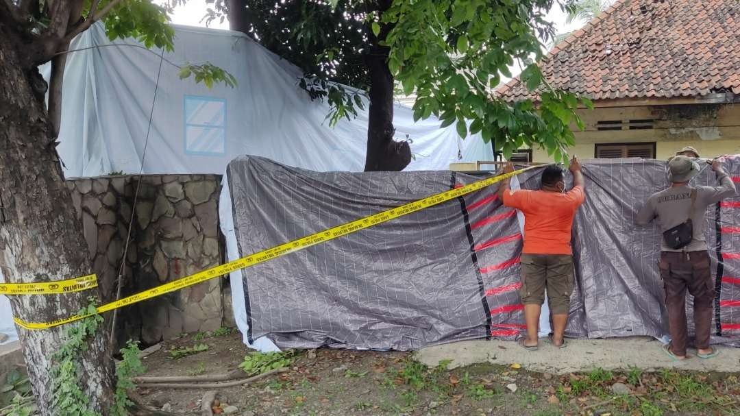 Petugas menutup lokasi kejadian dengan terpal dan garis polisi. (Foto: Fariz Yarbo/Ngopibareng.id)