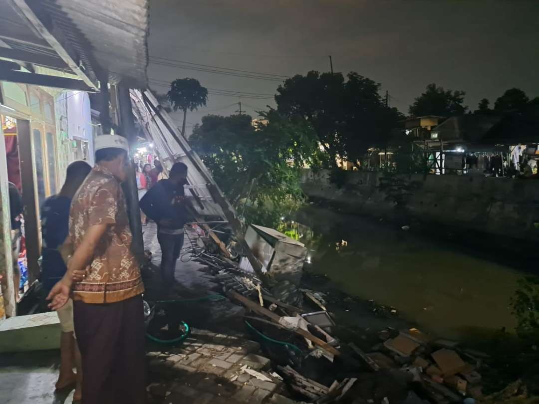 Warga menyaksikan kondisi plengsengan sungai ambrol, Rabu 6 Maret 2024 malam. (Foto: Pita Sari/Ngopibareng.id)