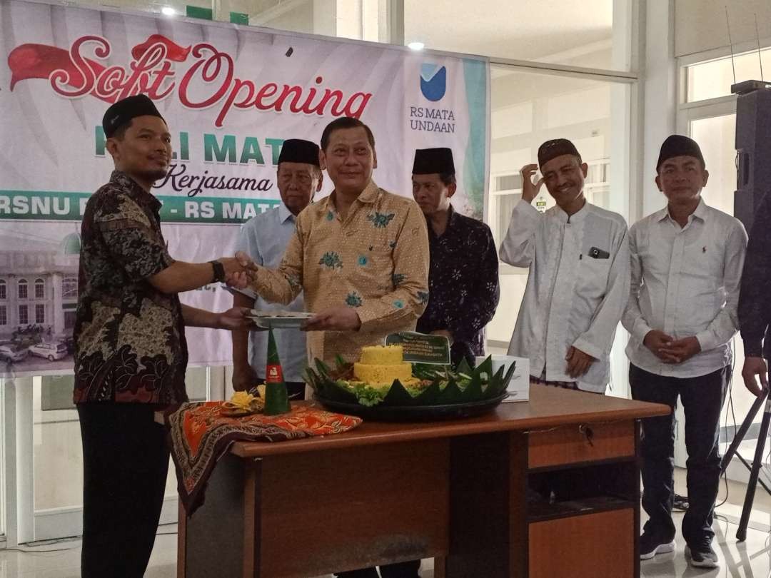 Direktur RS Mata Undaan dokter Sahata PH Napitupulu menyerahkan potongan tumpeng tanda diresmikannya polimata kepada Direktur RS Nahdlatul Ulama Babat, dokter Faiz Dina Artika didampingi Ketua PC Nahdlatul Ulama Babat dan tokoh lainnya (Foto : Imron Rosidi/ngopibareng.id)