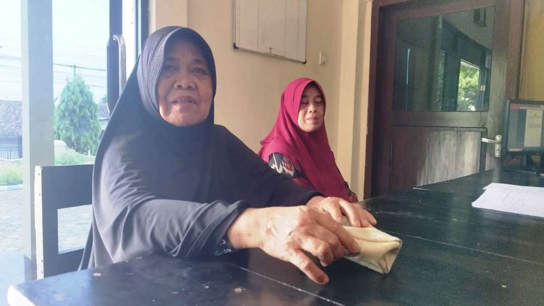 Saenah didampingi anaknya melapor ke Polsek Glagah (foto: Muh Hujaini/Ngopibareng.id)