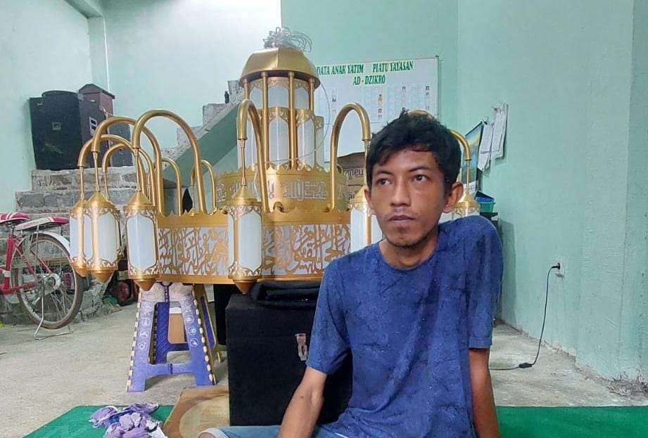 Erwin Adi Pastika di dekat lampu gantung bermotif kaligrafi karyanya. (Foto: Ikhsan Mahmudi/Ngopibareng.id)