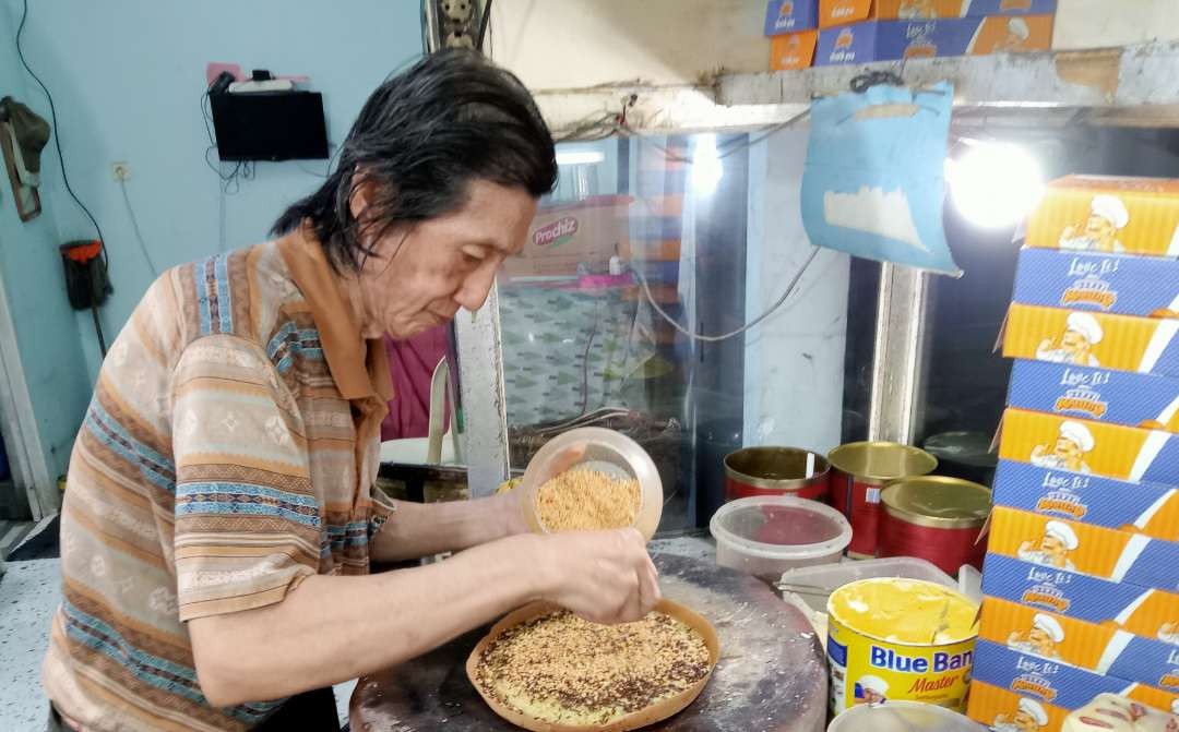 Kok Alung, eksis sebagai penjual martabak Bangka sejak 1982 atau selama 42 tahun. (Foto: Asmanu Sudarso/Ngopibareng.id)