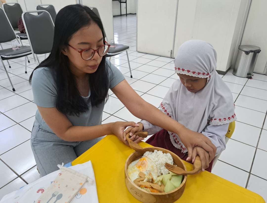 Alicia saat membantu Aulia menggunakan set alat makan Tactus khusus Tunanetra. (Foto: Pita Sari/Ngopibareng.id)