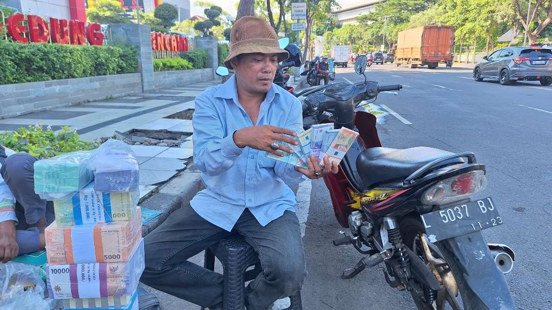 Salah satu penyedia jasa penukaran uang, Muhammad Lodyeh saat menjajakan jasanya di Jalan Pahlawan, Surabaya. (Foto: Julianus Palermo/Ngopibareng.id)