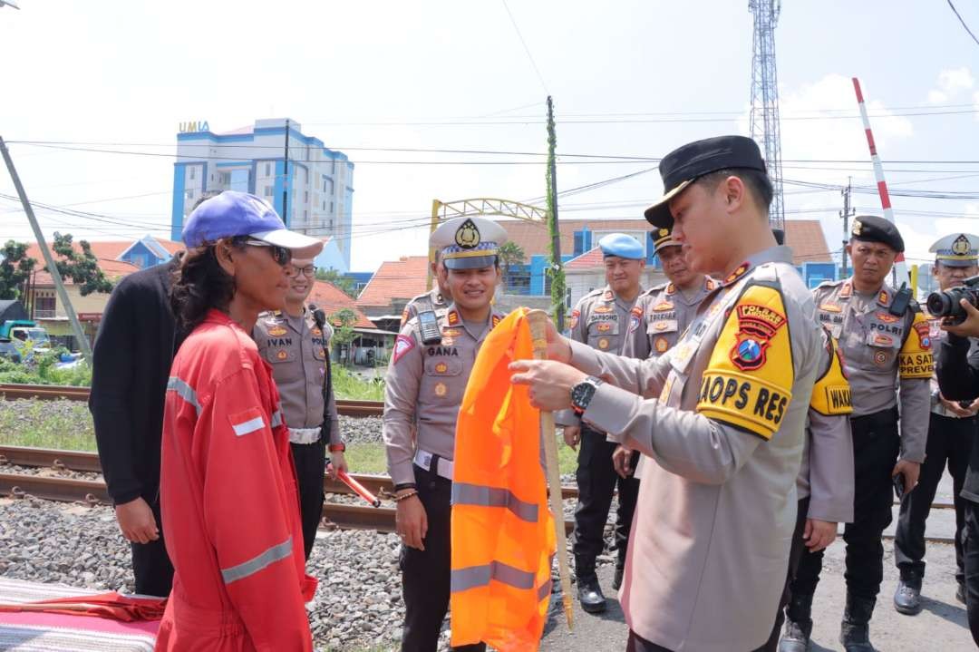 Kapolres Lamongan AKBP Bobby Chandra Putra sedang menyerahkan perangkat jaga lintasan kereta api. (Foto: Istimewa)