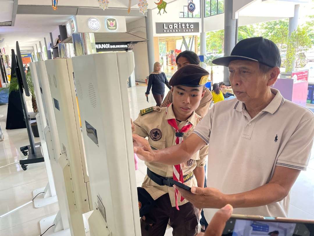 Salah satu anggota Pramuka, saat menjadi sukarelawan membantu salah seorang penumpang di Stasiun Surabaya Gubeng. (Foto: Julianus Palermo/Ngopibareng.id)