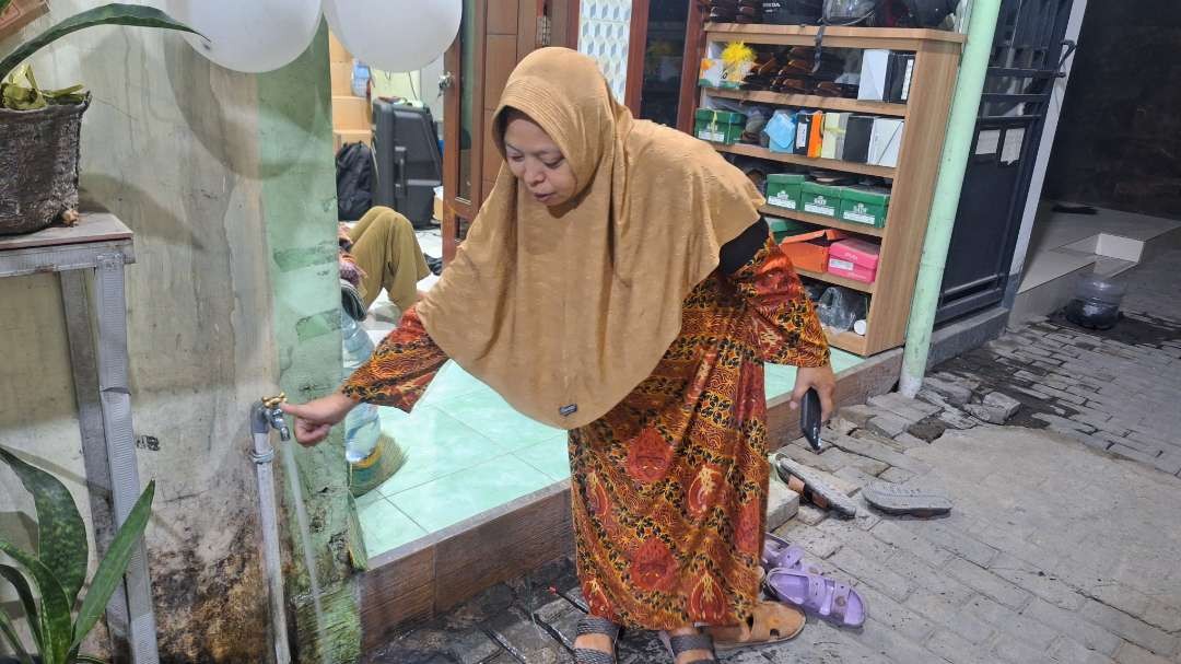 Rosulin, salah satu pengurus RW I, Kelurahan Nginden Jangkungan, Kecamatan Sukolilo, Surabaya, saat menunjukkan air PDAM yang sudah normal setelah pengerjaan box culvert kurang lebih tiga minggu lamanya. (Foto: Julianus Palermo/Ngopibareng.id)