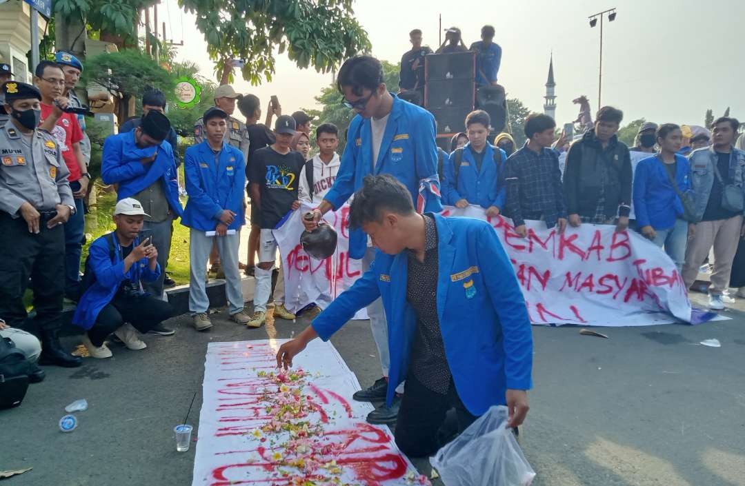 Dalam aksi unjuk rasa, mahasiswa dari PC PMII Tuban melakukan aksi tabur bunga di depan kantor Bupati Tuban. (Foto: Khoirul Huda/Ngopibareng.id)