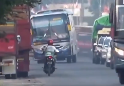 Bus Sumber Rahayu yang menyalip kendaraan di depannya di sebuah jalan raya. Padahal di depannya terdapat pengendara sepeda motor. (Foto: tangkapan layar X)