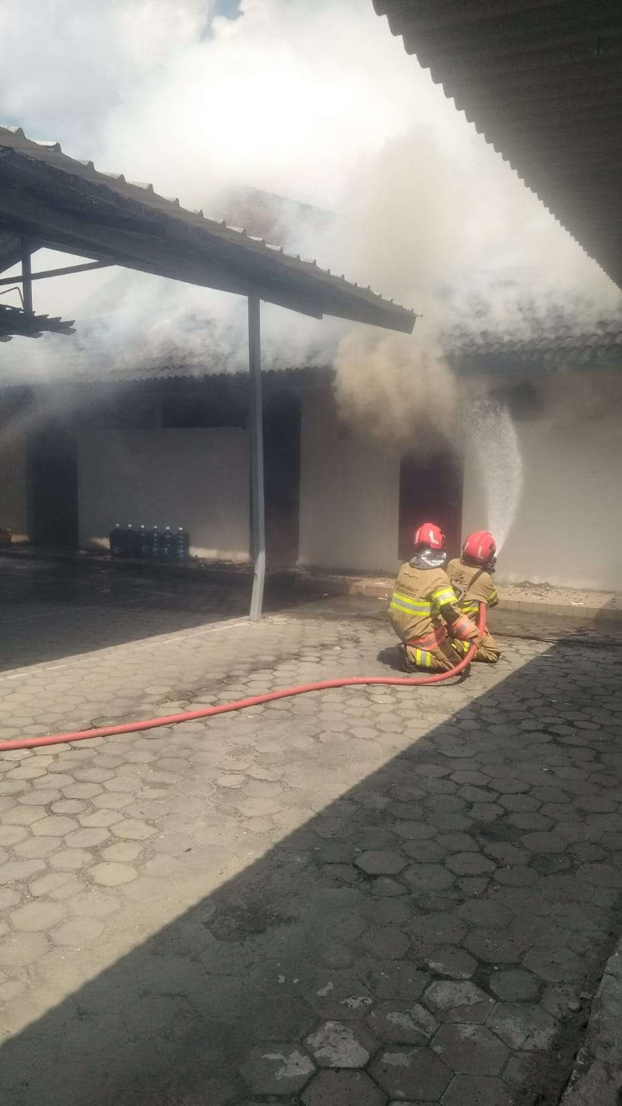 Petugas Damkarmat Bojonegoro melakukan penyemprotan di gudang Bank BTPN Bojonegoro yang terbakar, pada Kamis 6 Mei 2024. (Foto: dok. damkarmat bojonegoro)