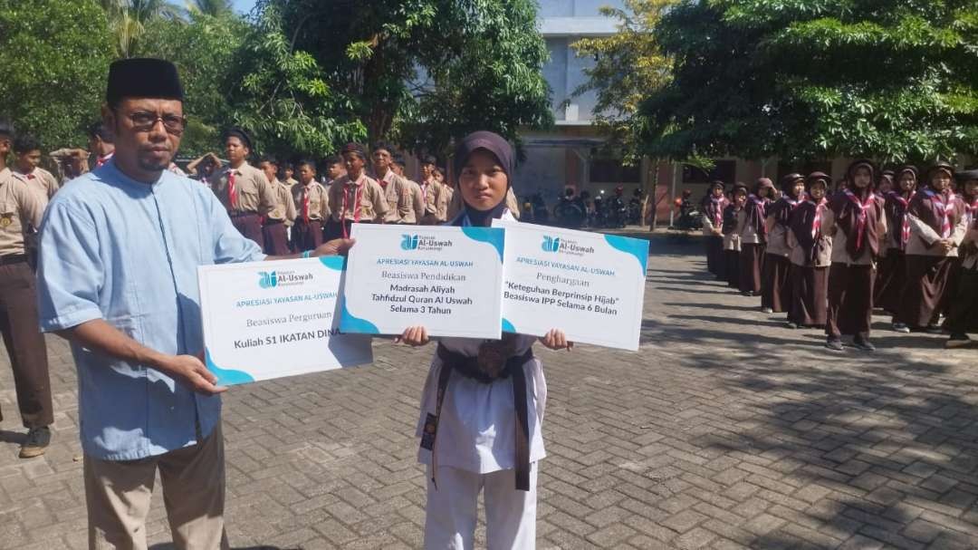 Sekretaris Yayasan Al Uswah menyerahkan beasiswa kepada Almira (Foto : Muh Hujaini/ngopibareng.id)