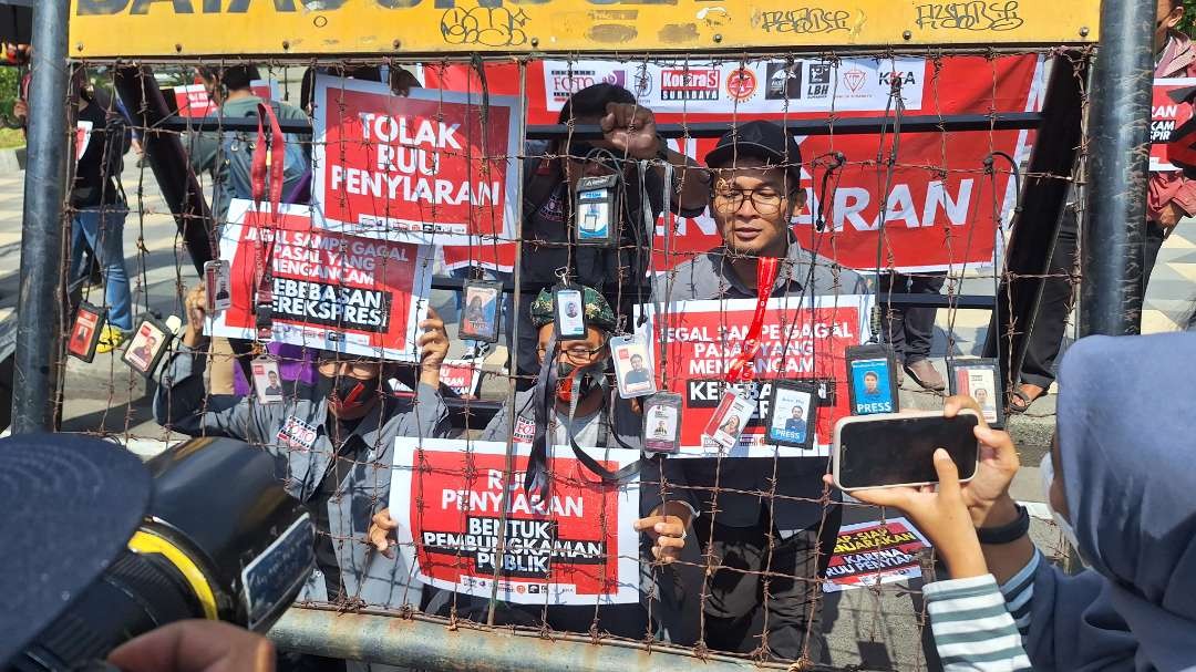 Aksi penggantungan kartu pers oleh para jurnalis di Surabaya yang berdemonstrasi dalam demo penolakan RUU Penyiaran, di Gedung Grahadi Surabaya, Selasa 28 Mei 2024. (Foto: Julianus Palermo/Ngopibareng.id)