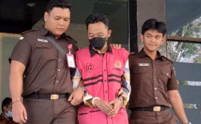 Mantan Kades Maskuning Kulon Kecamatan Pujer berinisial UR mengenakan rompi merah jambu digiring penyidik kejaksaan menuju Lapas Bondowoso, Rabu 12 Juni 2024.(Foto: Guido/Ngopibareng.id)