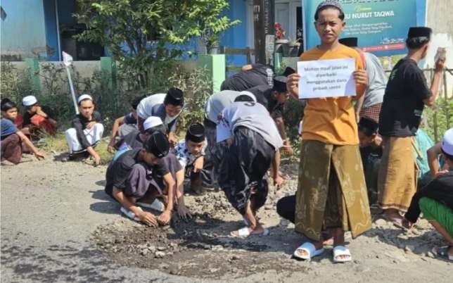 Santri gotong royong memperbaiki jalan rusak berlubang di Cermee yang tak kunjung diperbaiki Pemkab  Bondowoso. (Foto: Dokumentasi Ponpes Nurut Taqwa)