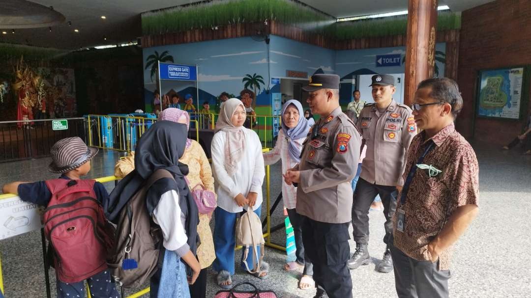 Kapolsek Kabat AKP Kusmin menyapa masyarakat yang sedang berwisata (foto: Muh Hujaini/Ngopibareng.id)