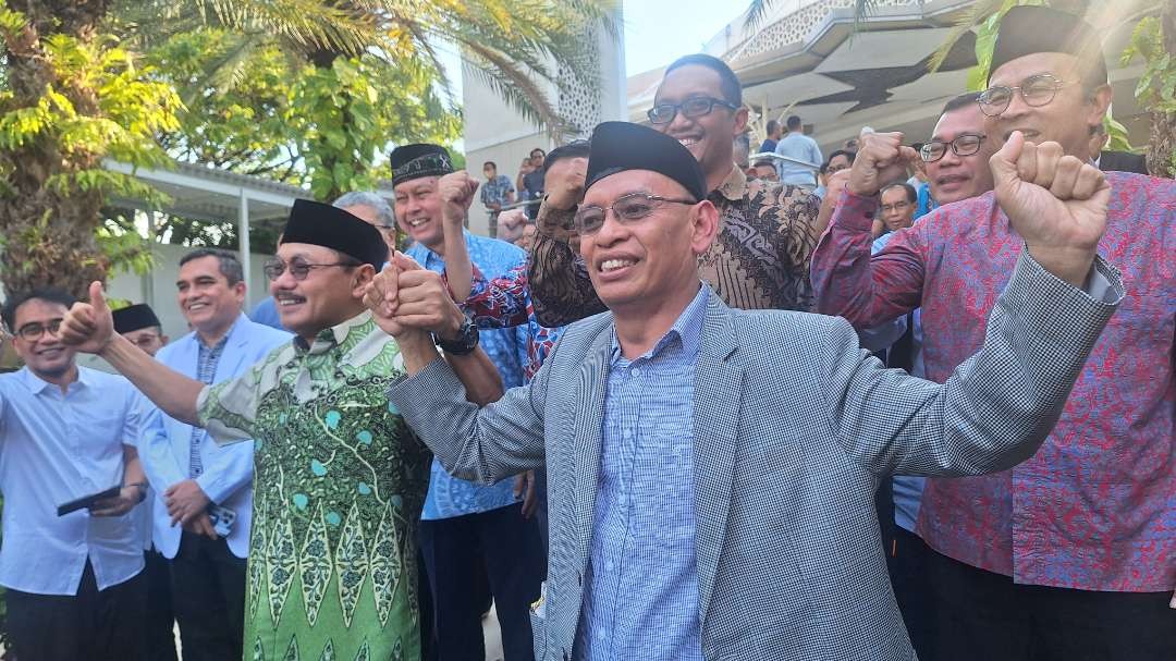 Prof. Budi Santoso (kiri berbatik), yang jabatannya dipulihkan sebagai Dekan FK Unair, bergandeng tangan dengan Rektor Unair Prof Mohammad Nasih (kanan berjas abu), di halaman Masjid Ulul Azmi, Kampus C Universitas Airlangga, Selasa 9 Juli 2024. (Foto: Julianus Palermo/Ngopibareng.id)