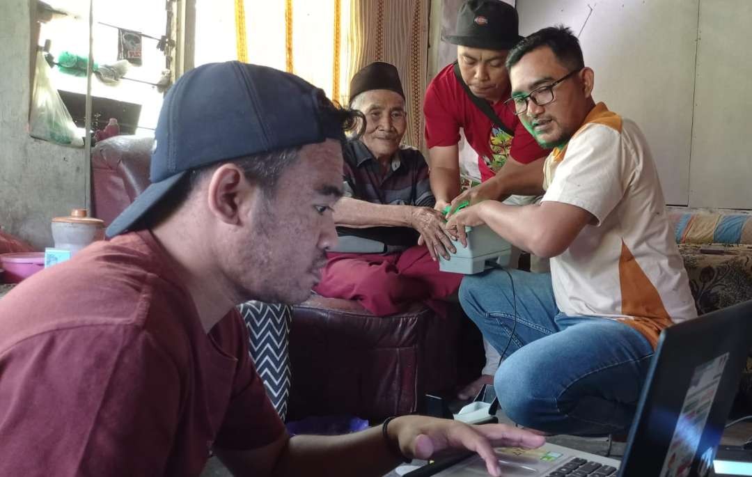 Petugas Dispendukcapil Jember saat proses perekaman adminduk di rumah kakek Abdul Ghafar. (Foto: Rusdi/Ngopibareng.id)