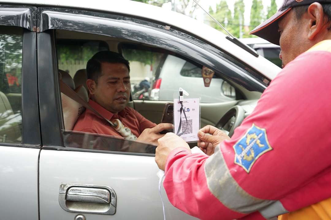 Potret juru parkir resmi Pemkot Surabaya yang menunjukkan scan kode batang QRIS kepada masyarakat yang hendak membayar retribusi parkir. (Foto: Humas Pemkot Surabaya)