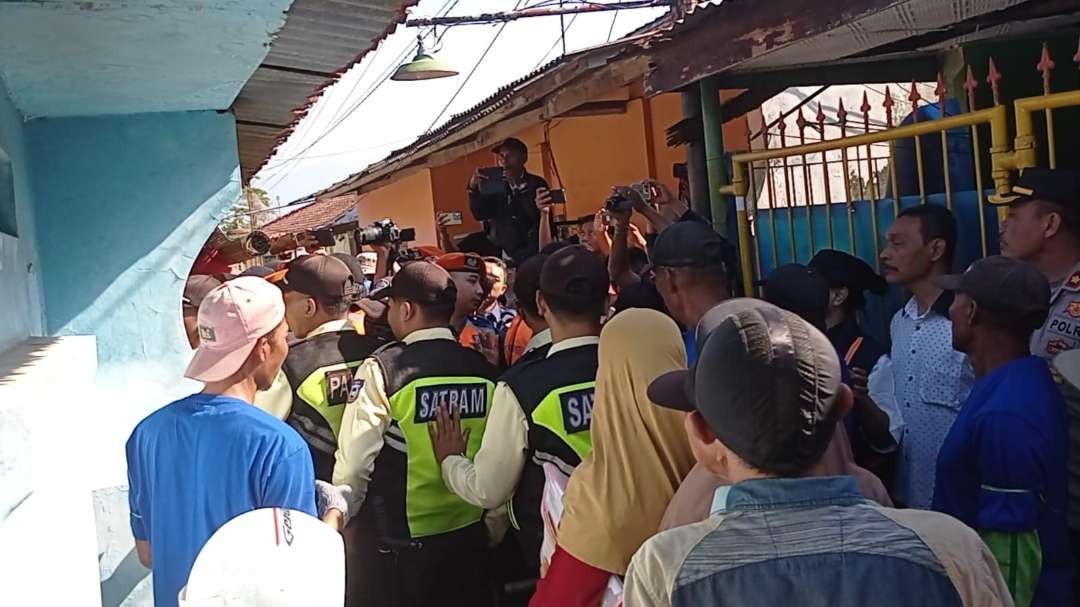 Warga dan petugas pengamanan memadati rumah warga yang akan dikosongkan oleh PT KAI Daop 9 Jember. (Foto: Rusdi/Ngopibareng.id)