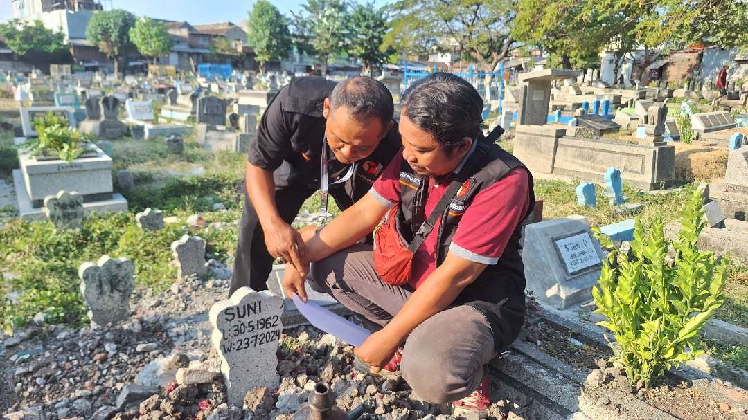 Petugas Panwascam Sawahan masuk kuburan saat memeriksa dan melakukan validasi data terhadap masyarakat yang sudah tutup usia, tapi masih masuk dalam DP4 di TPU Putat Gede. (Foto: Julianus Palermo/Ngopibareng.id)