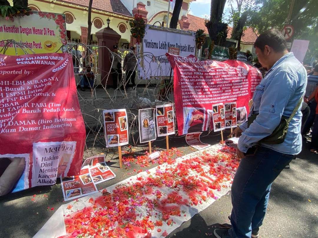 Taburan bunga, uang koin, dan spanduk dukungan dari massa aksi demonstrasi di PN Surabaya, terkait putusan bebas yang diterima terdakwa Gregorius Ronald Tannur. (Foto: Julianus Palermo/Ngopibareng.id)