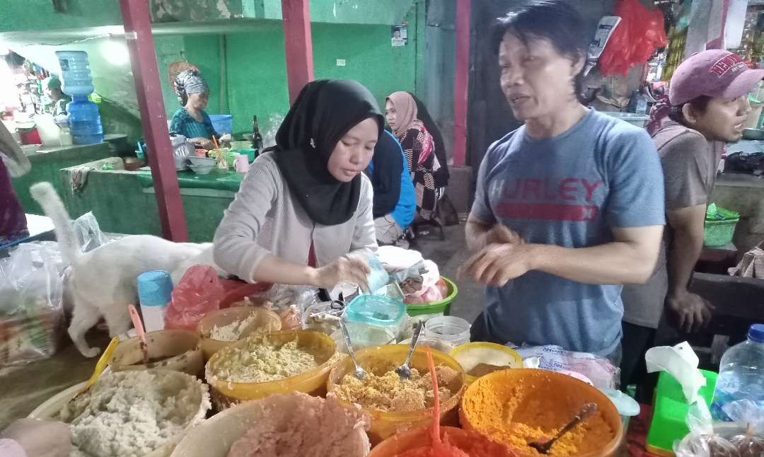 Pedagang 1001 bumbu masak di Pasar Pegirian Surabaya, Yos Fauzi bersama istrinya, Meri, sibuk melayani pelanggannya dari pagi. (Foto: Asmanu Sudarso/Ngopibareng.id)