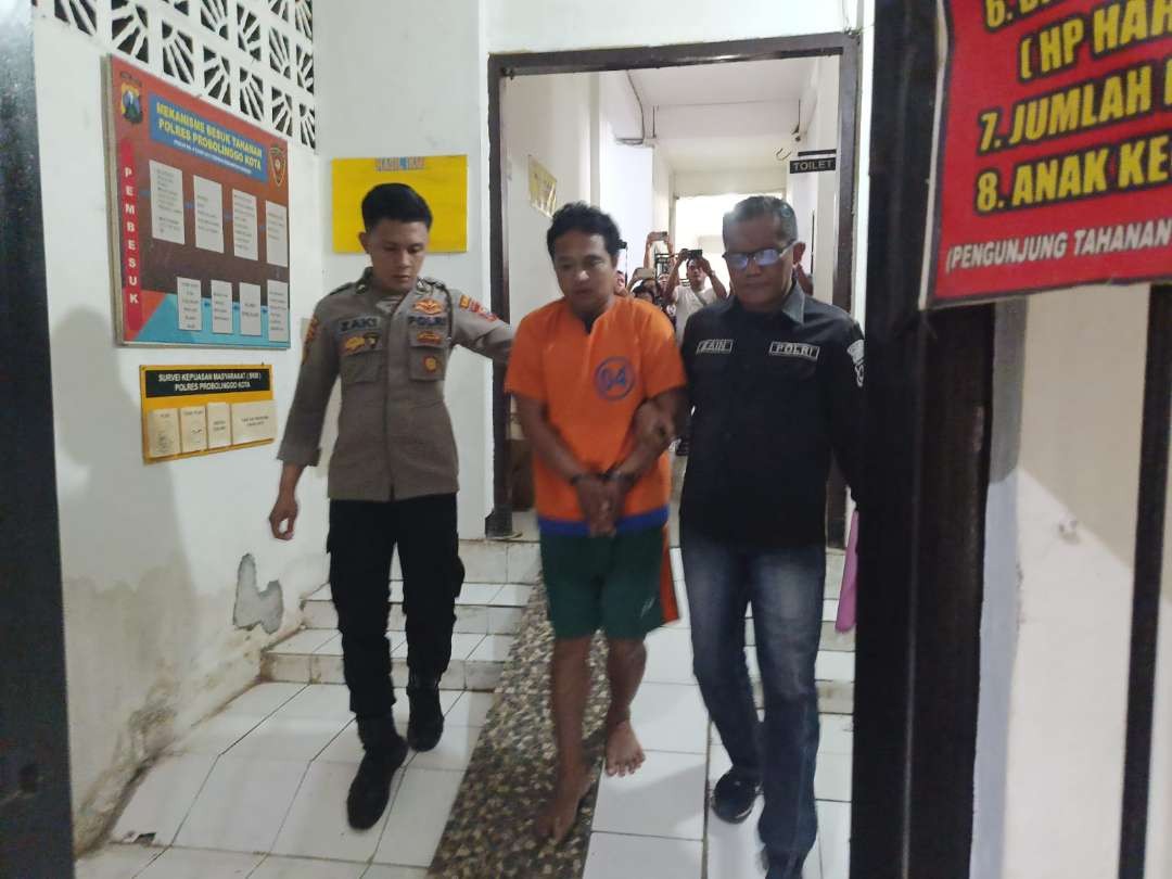 Dedi Susanto (tengah), 39 tahun, tersangka pembunuhan terhadap Maryam, 36 tahun dikawal polisi. (Foto: Polres Probolinggo Kota)