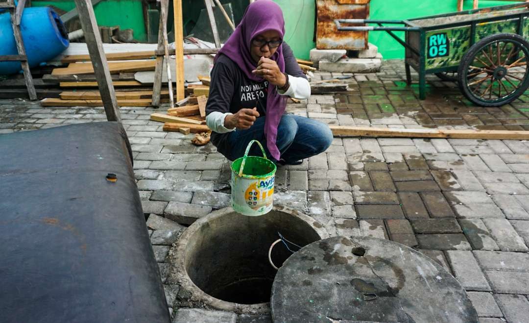 Wiwik saat menimba air sumur panas di Balai RW 5, Desa Boro, Tanggulangin (Foto: Aini/Ngopibareng.id)