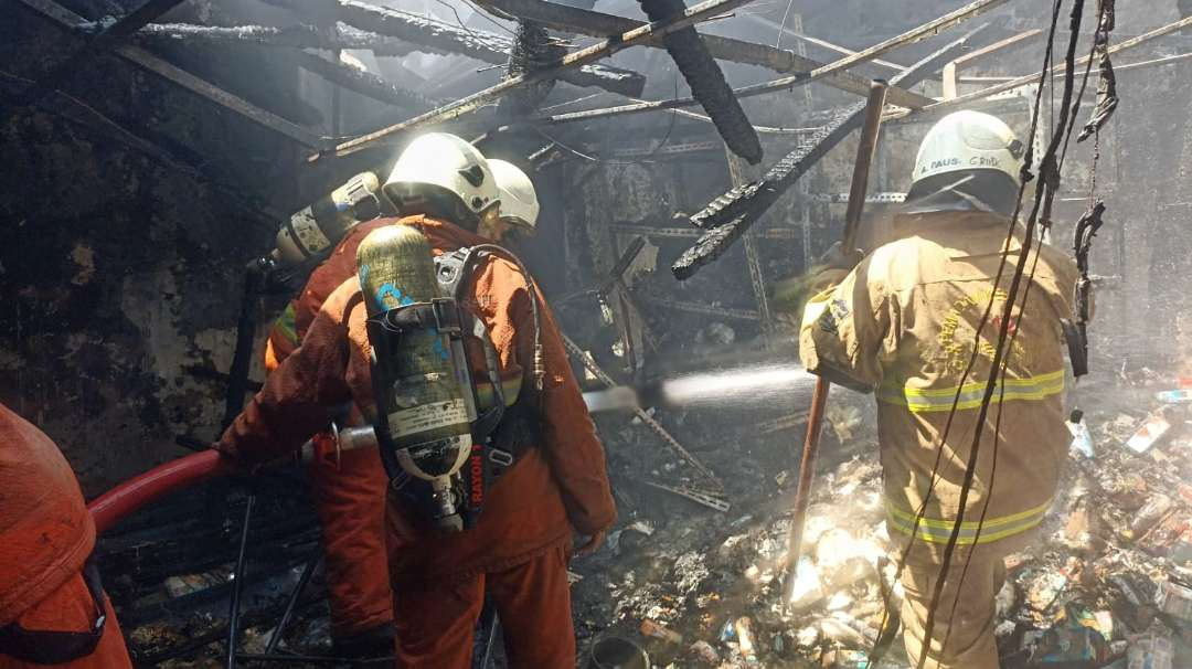 Petugas pemadam kebakaran sedang memadamkan api di sebuah rumah yang terbakar di Jalan Bulak Cumpat Barat Nomor 1, Kelurahan Bulak, Kecamatan Bulak, Kota Surabaya. (Foto: CC112)