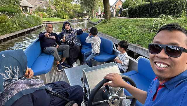 Sukemi (paling kiri) dan keluarga, naik punters atau perahu menyusuri kanal-kanal indah dan damai di Giethoorn, sebuah desa kecil di provinsi Overijssel, Belanda. (Foto:Ngopibareng.Id/Sukemi)