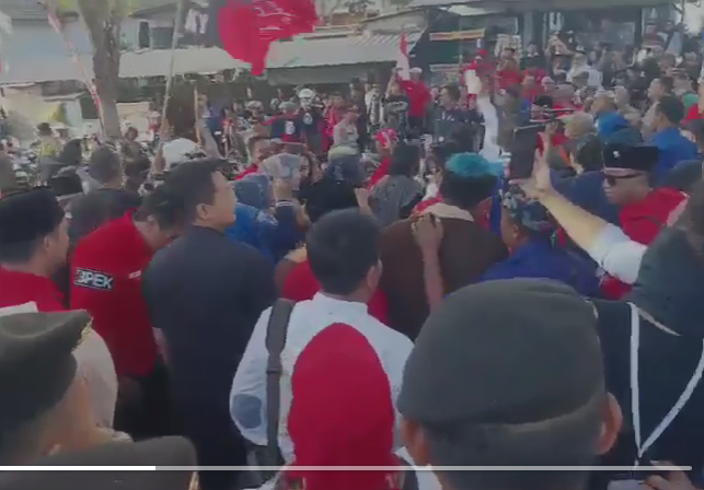 Oknum tim kampanye tampak menyebar uang di tengah kerumunan, Selasa 27 Agustus 2024. (Foto: Choirul Anam/Ngopibareng.id)