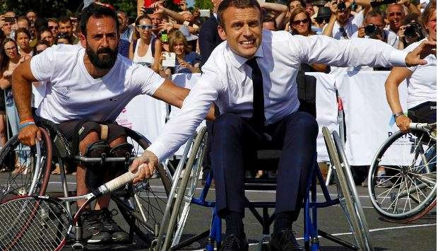 Gaya Presiden Prancis Emmanuel Macron berusaha memukul bola sambil duduk di kursi roda di Paris, Prancis. Kegiatan ini sebagai bentuk promosi Paris untuk menjadi kandidat tuan rumah Olimpiade dan Paralimpiade 2024.