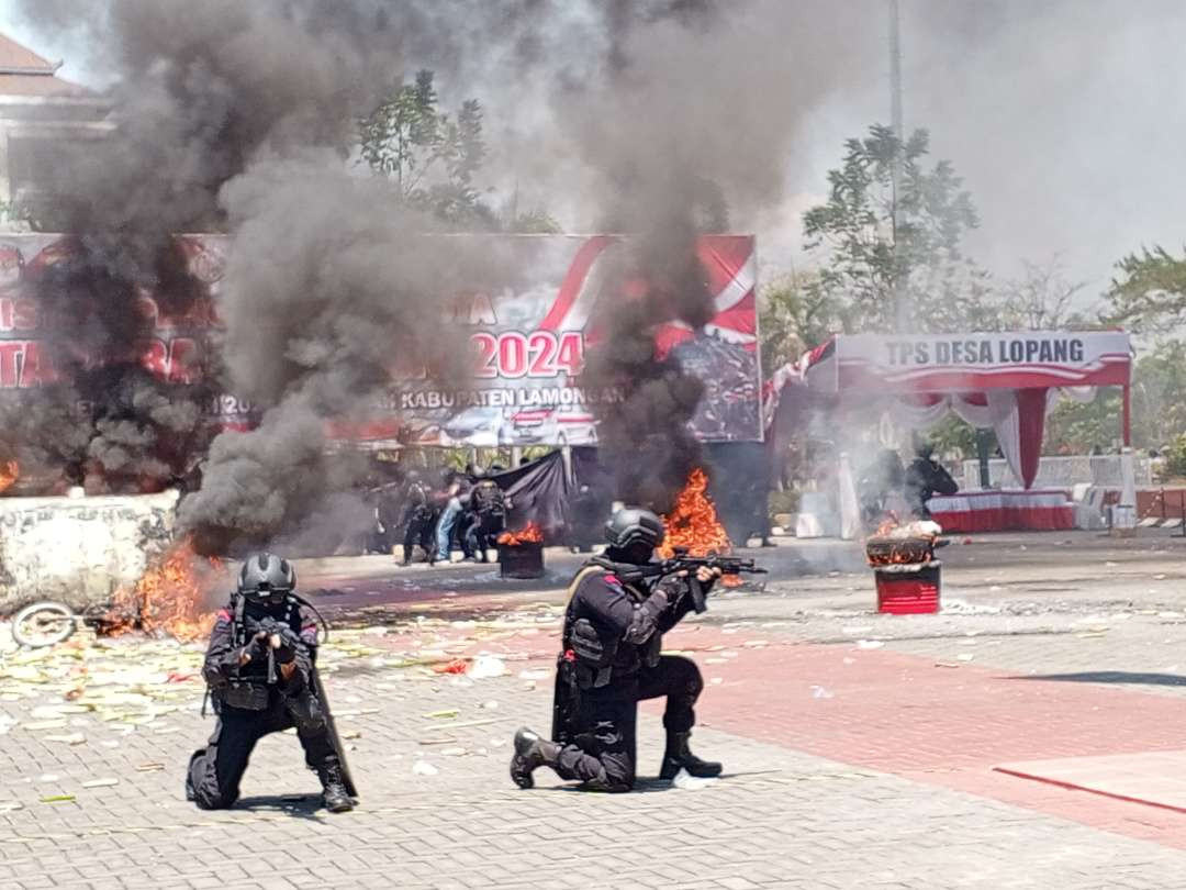 Pasukan Brimob mengamankan situasi mobil dan motor dibakar massa. (Foto: Imron Rosidi/Ngopibareng.id)