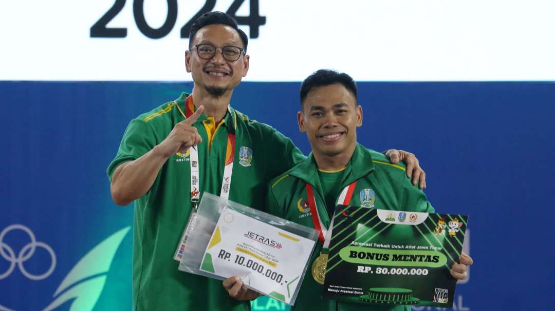 Ketua PABSI Jatim, Jeffry Tagore (kiri) saat menyerahkan bonus mentas kepada Eko Yuli yang meraih emas di kelas 67 Kg putra pada PON XXI 2024 Aceh-Sumut. (Foto: Fariz Yarbo/Ngopibareng.id)