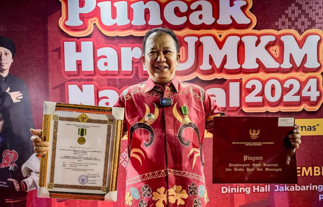 Bupati Jember Hendy Siswanto menunjukkan piagam penghargaan bakti koperasi dan UKM (Foto: Dokumentasi Diskominfo Jember)