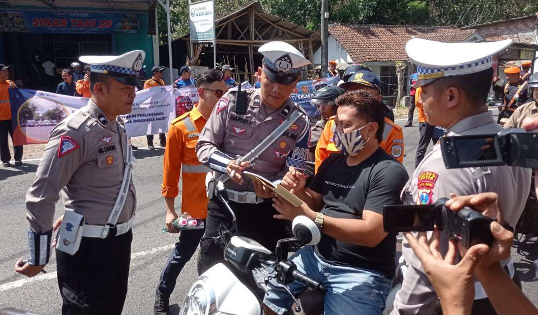 Pengendara motor mendapatkan sanksi karena tak memakai helm saat melintas di perlintasan sebidang (Foto: Rusdi/Ngopibareng.id)